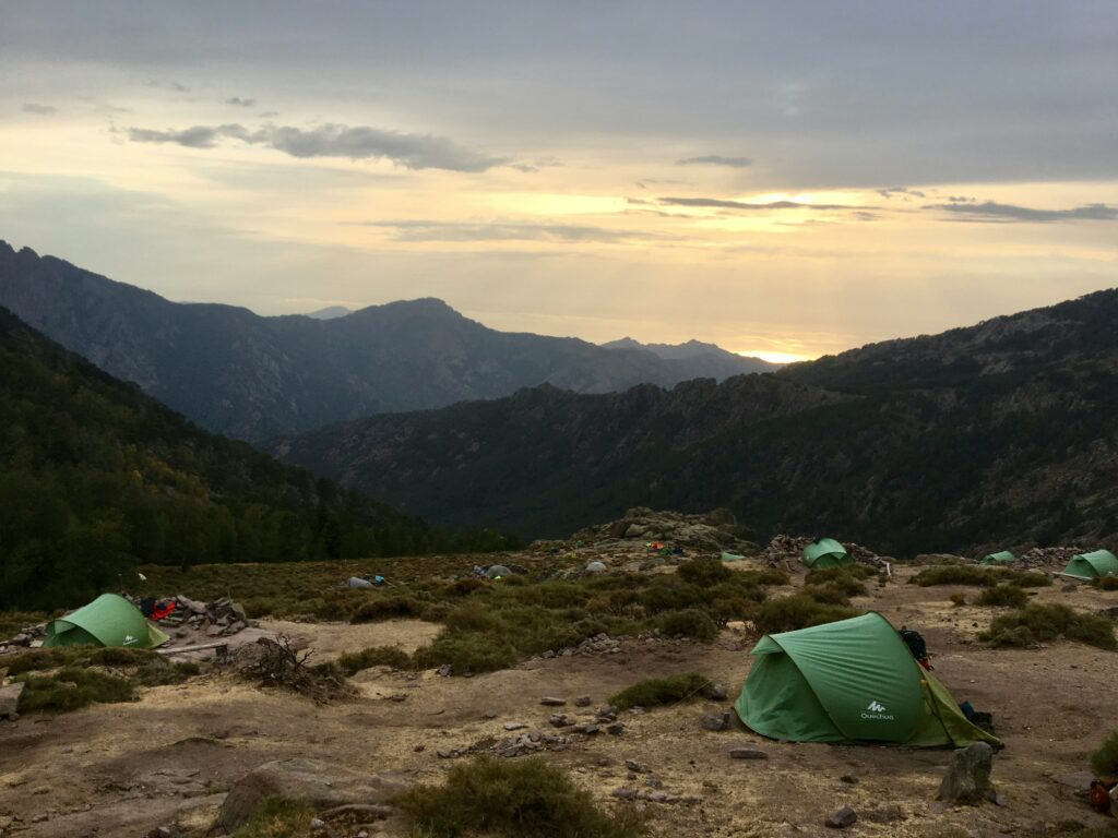 Tentes et randonneurs sur une aire de bivouac autorisée sur le GR20