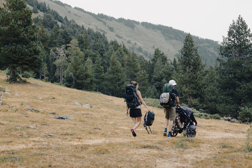 Famille en randonnée dans les Pyrénées avec bébé et enfant dans une poussette tout-terrain