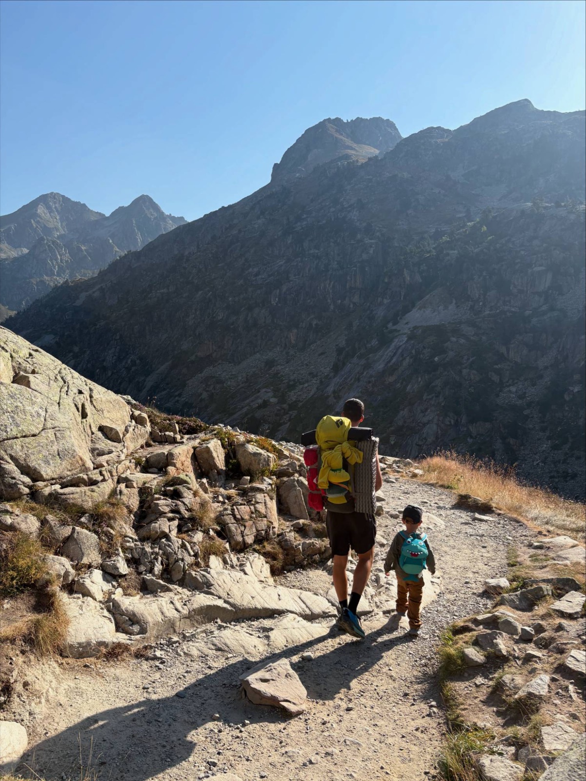 Père et enfant randonnant sur un sentier de crête dans les Pyrénées, sommets en arrière-plan