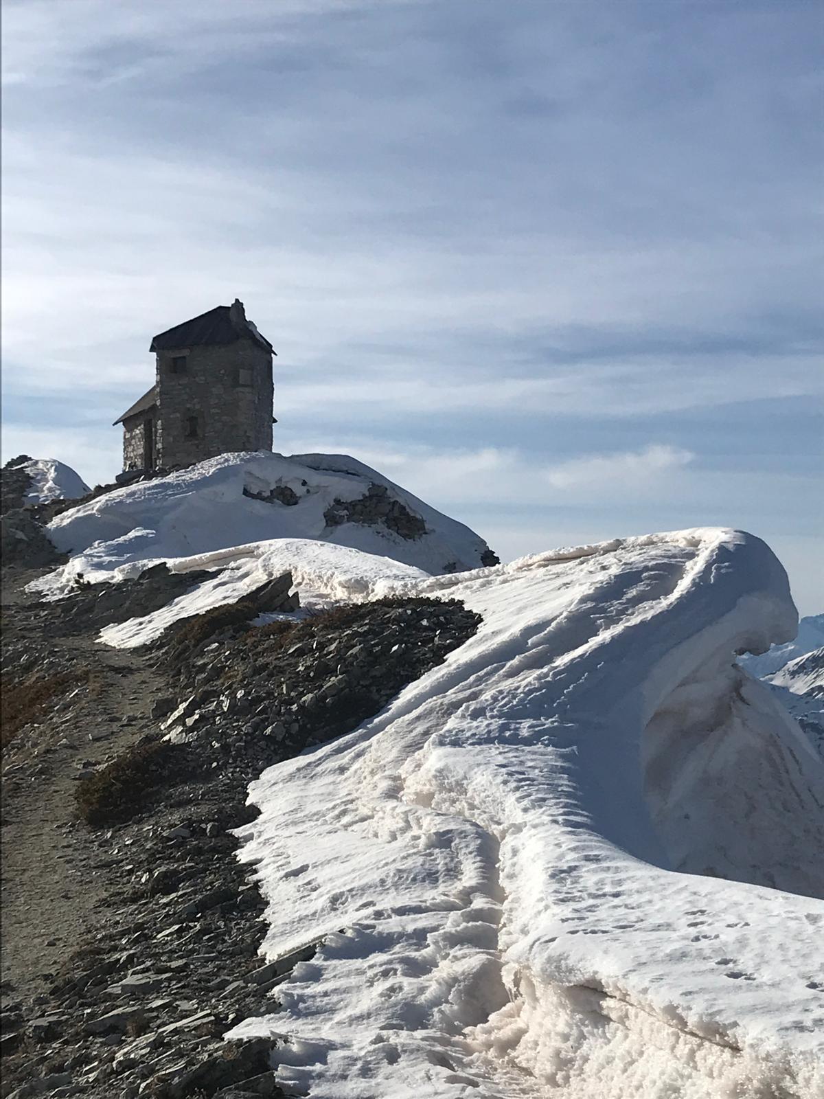 Petit oratoire de pierre sur une crête enneigée du Queyras